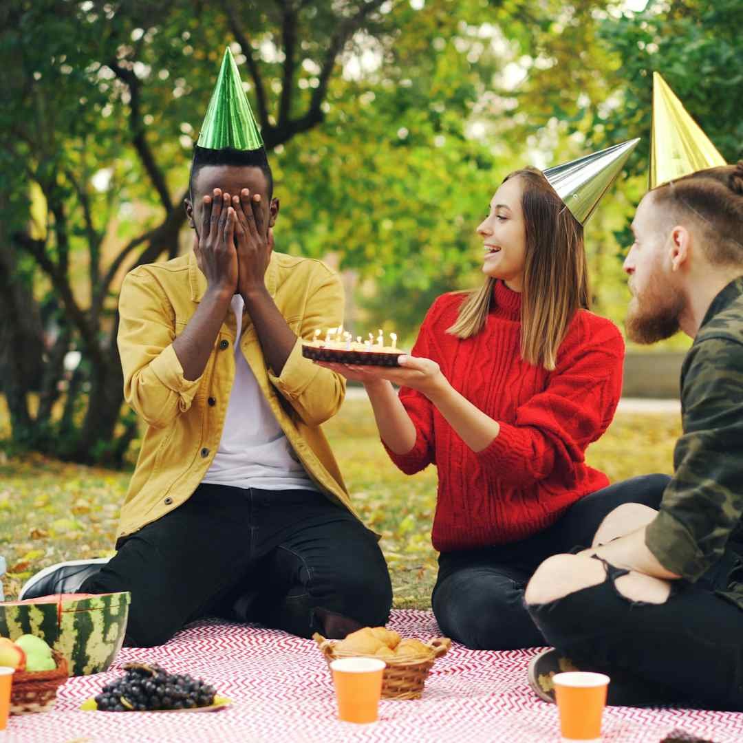 Friends celebrating a birthday with cake outdoors, happy birthday blessings for a friend