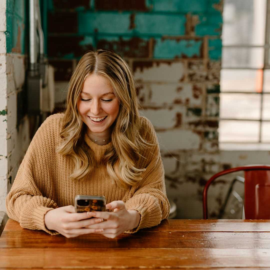 Woman at a table checking her phone, flirty absolutely pick up lines for dating apps and DMs