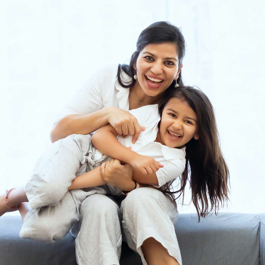 Woman holding a laughing child on a sofa, happy birthday blessings for son and daughter